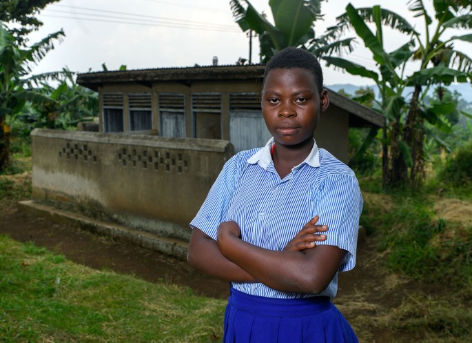 Janet Nyakasiki in front of a latrine building